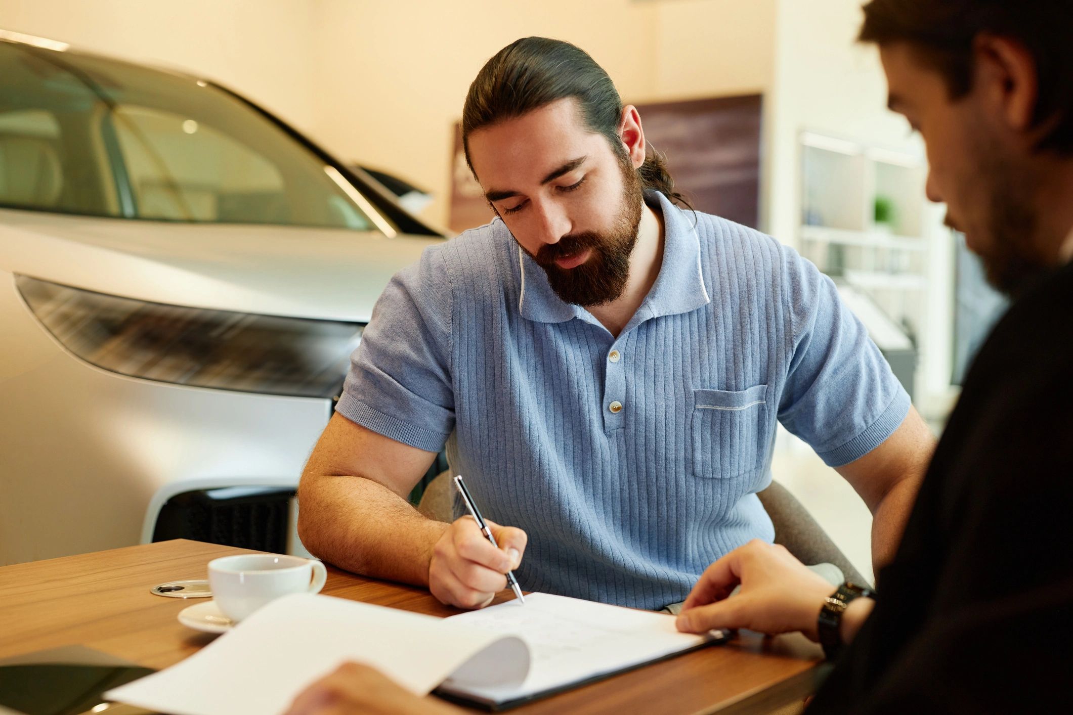 Customer signing paperwork at a dealership desk
