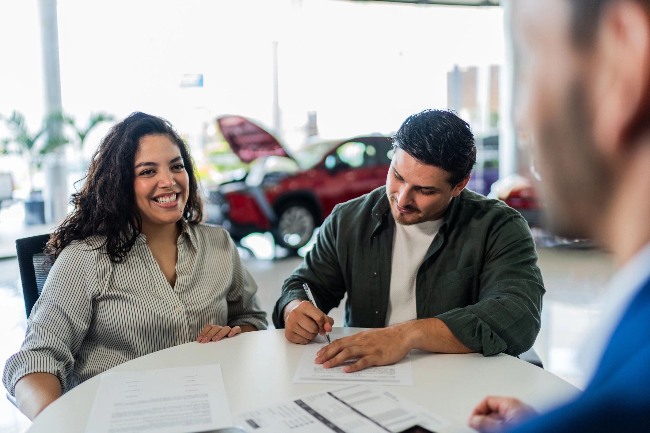 Couple completing paperwork at a car dealership